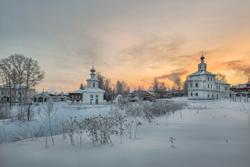 Ancient architecture is surrounded by tall white drifts and orange sunset skies.