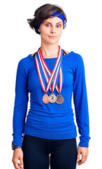 Beautiful young woman with short hair wearing winner medals thinking attitude and sober expression looking self confident