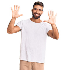 Young hispanic man wearing casual white tshirt showing and pointing up with fingers number ten...