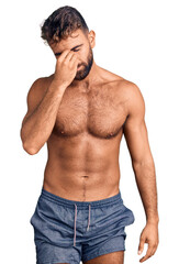 Fototapeta premium Young hispanic man wearing swimwear shirtless tired rubbing nose and eyes feeling fatigue and headache. stress and frustration concept.