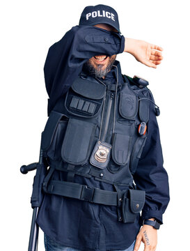 Young handsome man wearing police uniform covering eyes with arm smiling cheerful and funny. blind concept.