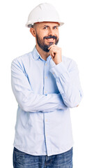 Young handsome man wearing architect hardhat looking confident at the camera with smile with crossed arms and hand raised on chin. thinking positive.