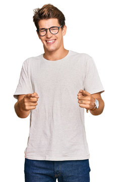 Handsome caucasian man wearing casual clothes and glasses pointing fingers to camera with happy and funny face. good energy and vibes.