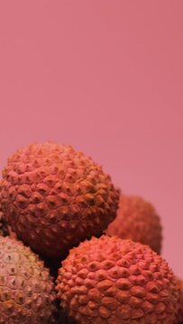 Lychee fruits, rotation in circle. tropical fruit lychee, Turning. selective focus. Lychee fruits on a pink background. vertical video