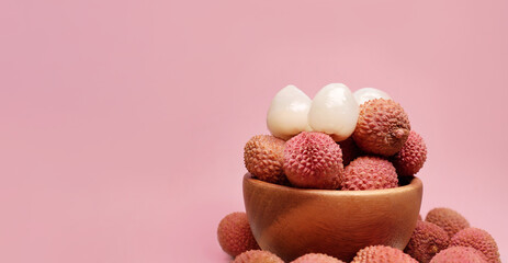 Lychee fruits in a wooden bowl on a pink background. tropical fruit lychee, selective focus.  