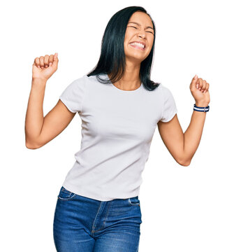 Beautiful hispanic woman wearing casual white tshirt dancing happy and cheerful, smiling moving casual and confident listening to music