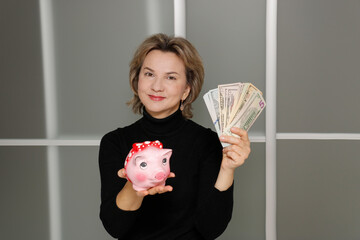 Fototapeta na wymiar joyful woman holding money and a piggy bank in her hands
