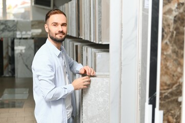 Young man choosing tiles at building market