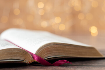 Open holy bible book with shiny golden bokeh light in the background. Close-up. Selective focus. ...