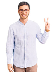 Handsome young man with bear wearing elegant business shirt and glasses smiling looking to the camera showing fingers doing victory sign. number two.