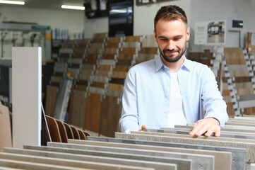 Young man choosing tiles at building market