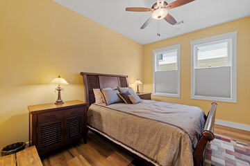 bedroom has wooden floors and walls with white trim, a bed frame and ceiling fan