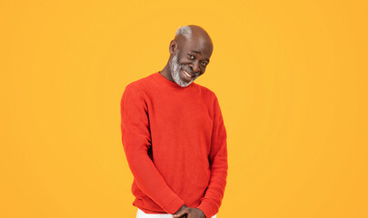 Smiling confident senior man in a red sweater and hat standing with hands in pockets