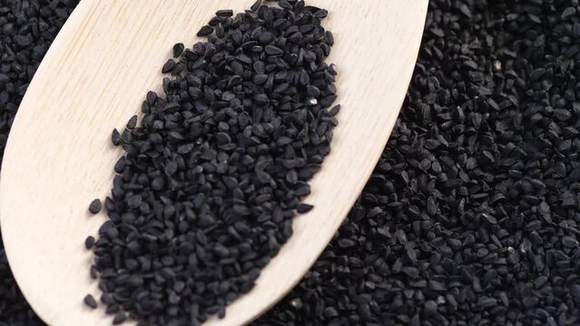 black cumin seeds in a wooden spoon rotation. macro black cumin seeds. oriental spices. black cumin harvest