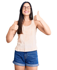 Young beautiful caucasian woman wearing casual clothes and glasses success sign doing positive gesture with hand, thumbs up smiling and happy. cheerful expression and winner gesture.