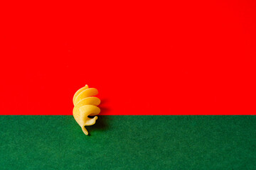 Alone fusilli pasta against a bold red and green background, italian pasta concept