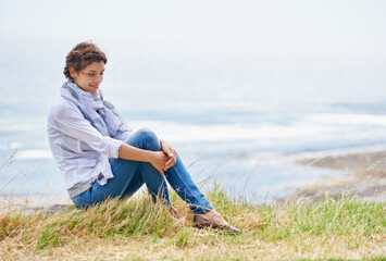 Naklejka na ściany i meble Woman, thinking and relax in nature at beach with happiness, gratitude and peace on holiday or vacation. Ocean, mock up and person on hill at the sea with ideas for future, travel and environment