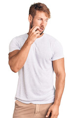 Young caucasian man wearing casual white tshirt looking stressed and nervous with hands on mouth biting nails. anxiety problem.