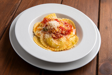 Piatto di deliziosi ravioli ripieni di ricotta e conditi con pomodoro e parmigiano, pasta italiana, cibo europeo 