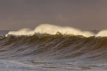 Spraying breaking waves at sunset