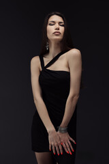 Fototapeta premium A woman elegantly poses for a photograph in a stylish black dress.