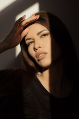 A woman with striking features poses in a photography studio, her face artistically divided by...