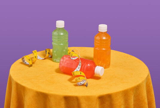 Brightly colored juices in plastic bottles and yellow measuring tape. Fitness concept.