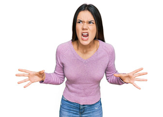 Young hispanic girl wearing casual clothes crazy and mad shouting and yelling with aggressive...