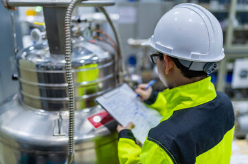 Asian engineer working at Operating hall,Thailand people wear helmet  work,He worked with diligence and patience,she checked the valve regulator at the hydrogen tank.