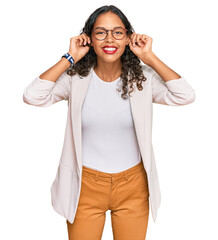 Young african american girl wearing business clothes smiling pulling ears with fingers, funny...