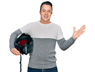 Handsome young man holding motorcycle helmet celebrating victory with happy smile and winner expression with raised hands