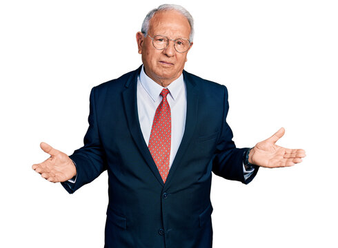 Senior man with grey hair wearing business suit and glasses clueless and confused with open arms, no idea concept.