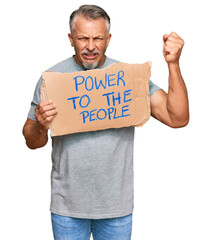 Middle age grey-haired man holding power to the people banner annoyed and frustrated shouting with anger, yelling crazy with anger and hand raised