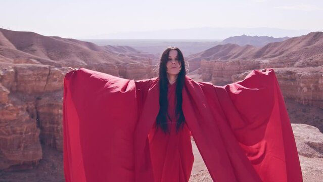 A woman in red is dancing on the cliff of the canyon.