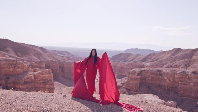The girl in red over the canyon cliff. Slow motion.