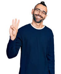Hispanic man with ponytail wearing casual sweater and glasses showing and pointing up with fingers number three while smiling confident and happy.