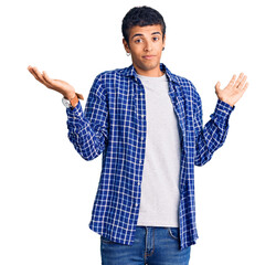 Young african amercian man wearing casual clothes clueless and confused expression with arms and...