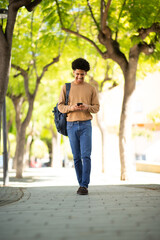 Fototapeta na wymiar African American man walks through the park with cellphone in hand