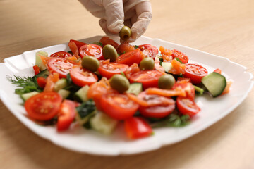 Olives are added to vegetable salad. Preparation of vegetable salad