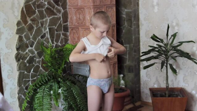 Kid Putting  T-Shirt, a boy puts on a white shirt on his body, a little boy gets dressed in the morning in the room