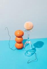 Fresh tangerine tower and frozen tangerine with glass against blue background. Still life