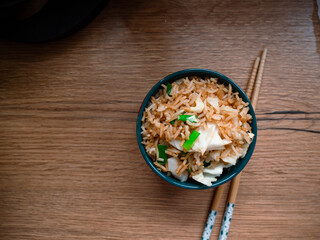 Petit bol de riz sautées avec de l'oignon vert et du chou posé sur un plan de travail en bois