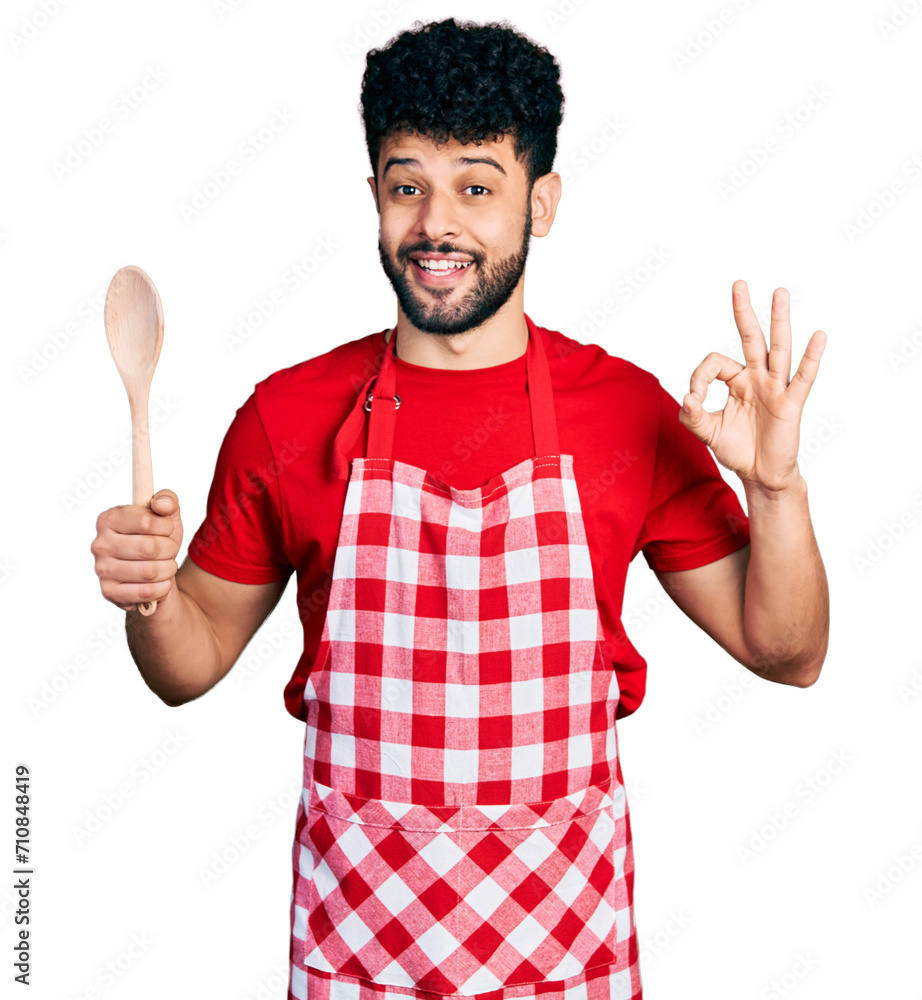 Sticker young arab man with beard wearing baker uniform holding wooden spoon celebrating crazy and amazed fo