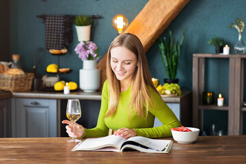 Young woman reading an interesting magazine at wooden table