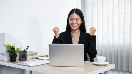 Young secretary woman smiling and looking on laptop with raising hands up when finished working job