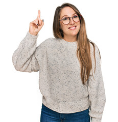Young blonde woman wearing casual sweater and glasses pointing finger up with successful idea. exited and happy. number one.
