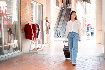 Asian woman tourist is dragging luggage with smiling and to shopping at duty-free shops