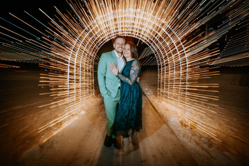  a couple embracing in a tunnel of dynamic light trails with a snowy ground beneath them.