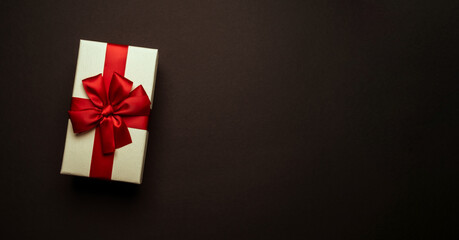 Light yellow gift box with red bow on black background