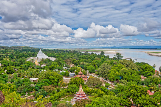view over the landscape of mingun with forest and pagodas and a dramatic cloudy sky